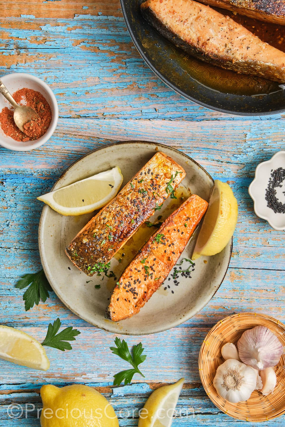 Garnished salmon with chopped parsley and lemon wedges.