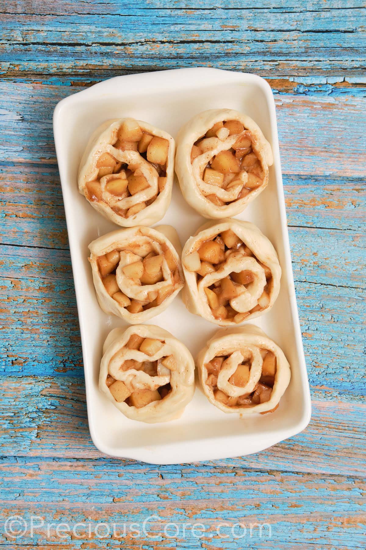 Cinnamon apple rolls placed into buttered casserole dish.