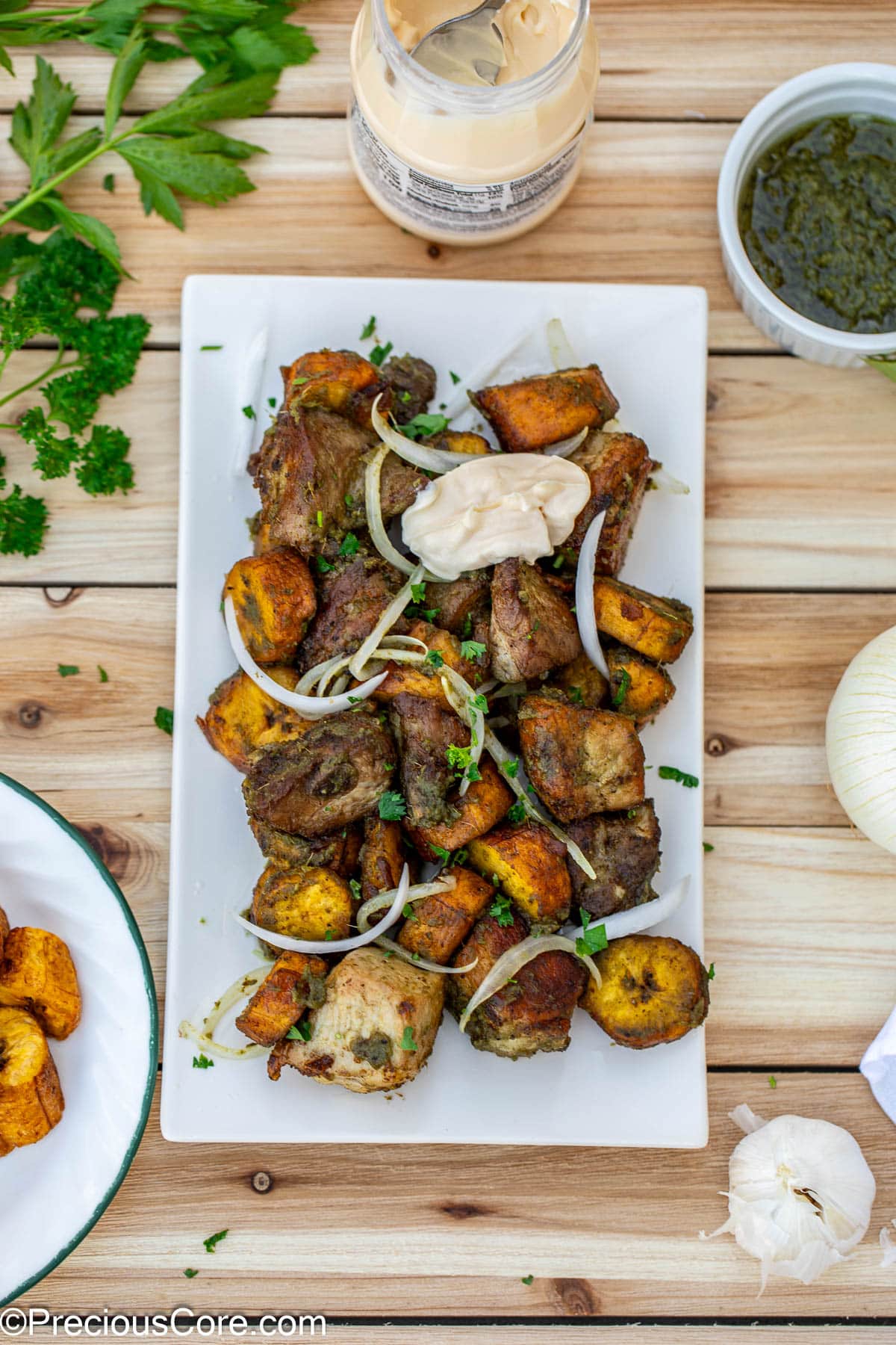 Round pieces of plantains and bite-size pork on a serving platter.