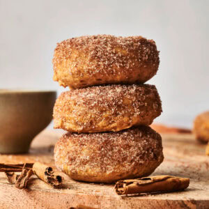 Three pumpkin spice doughnuts stacked on each other.