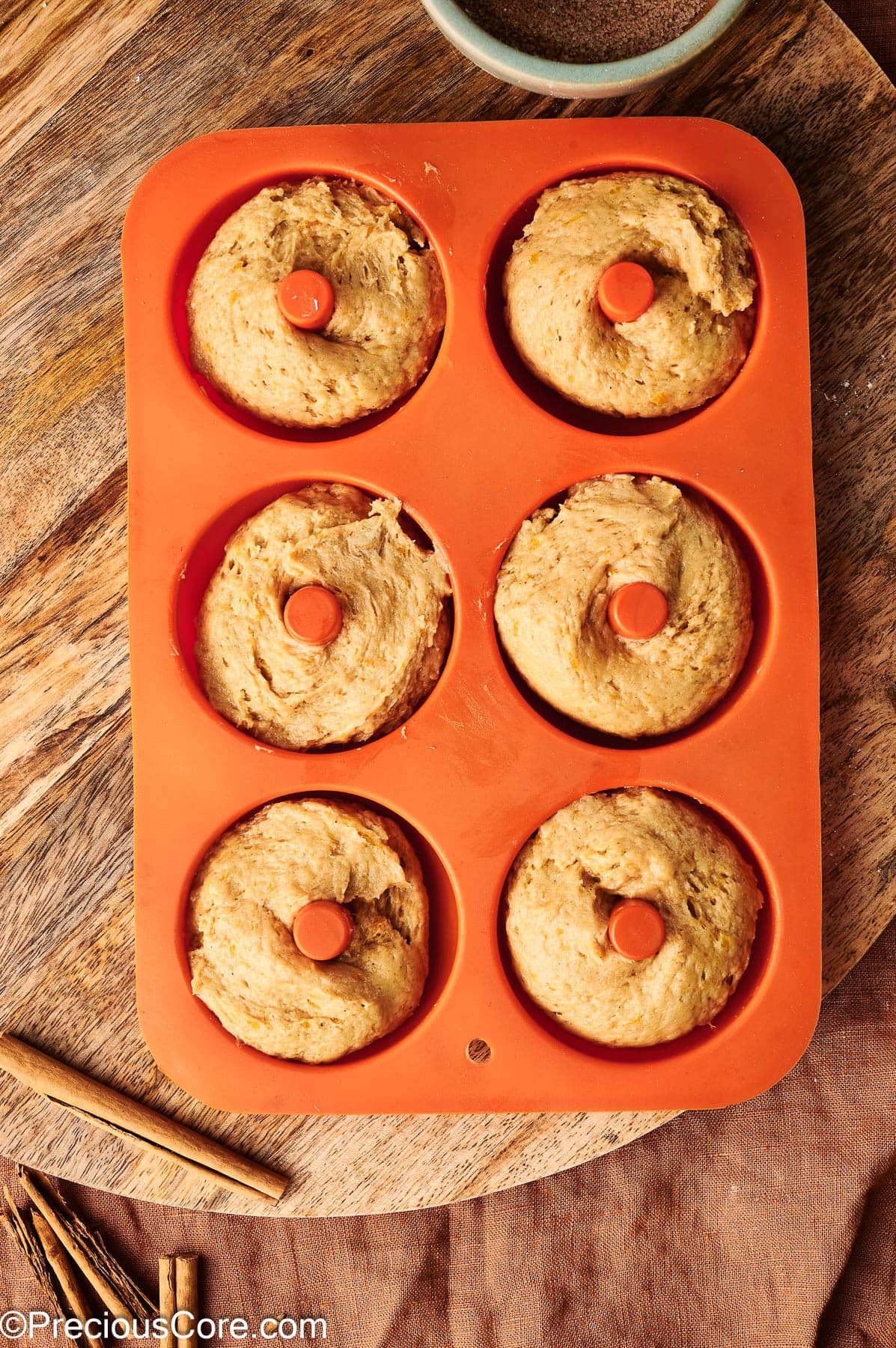 Pumpkin spice batter piped into doughnut pan.