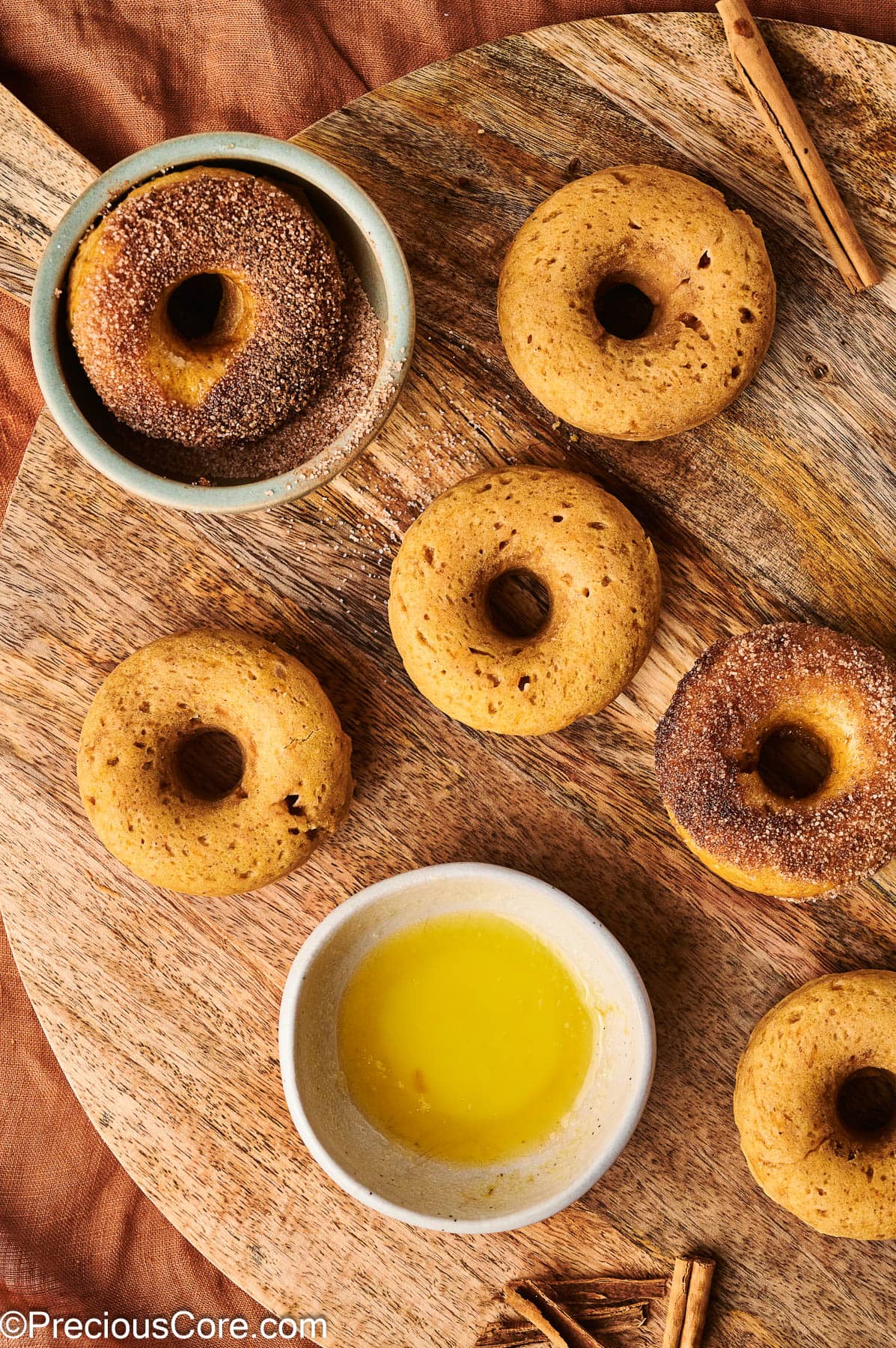 Two pumpkin doughnuts coated in cinnamon sugar.