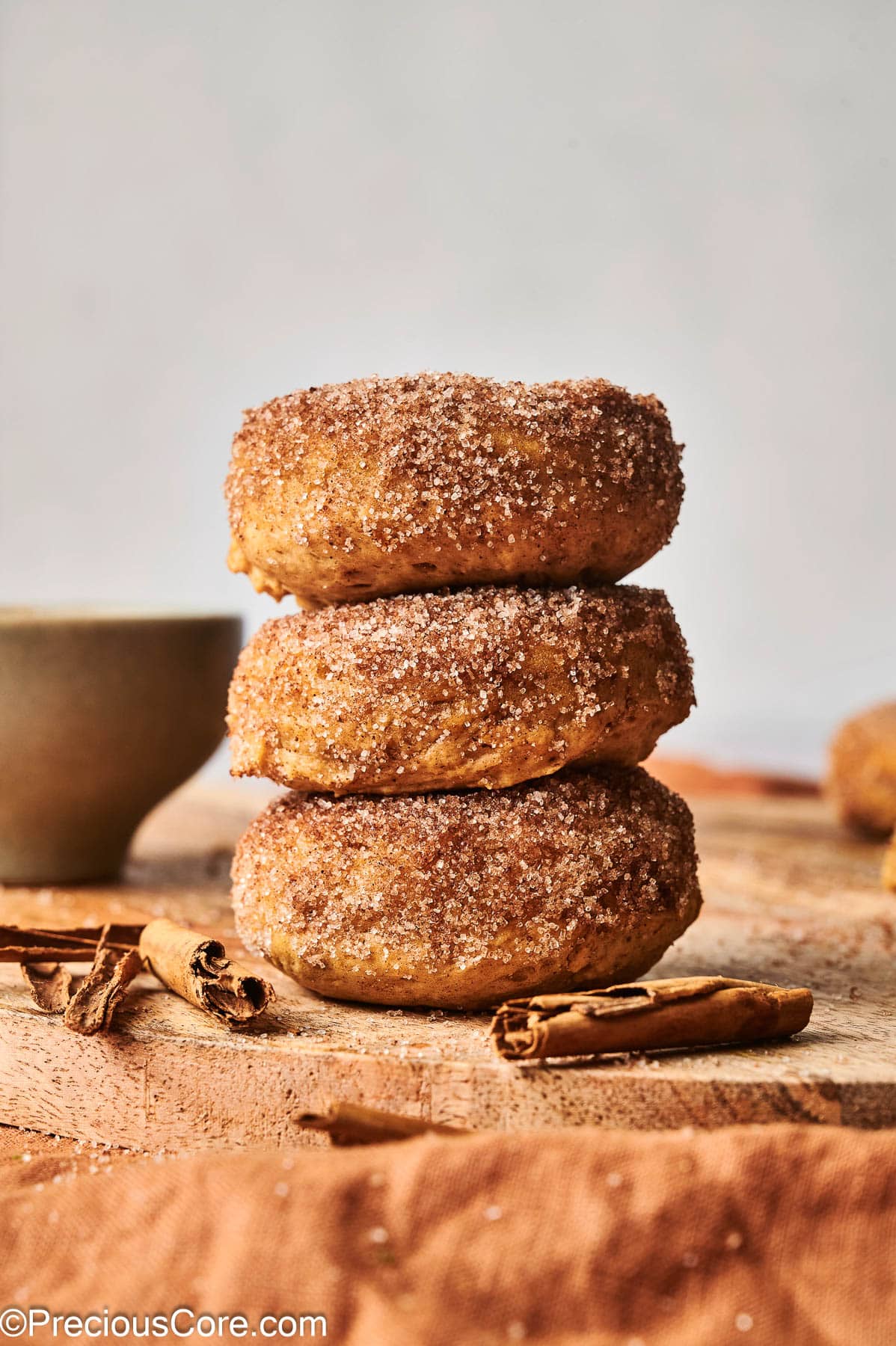 Three pumpkin spice doughnuts stacked on each other.