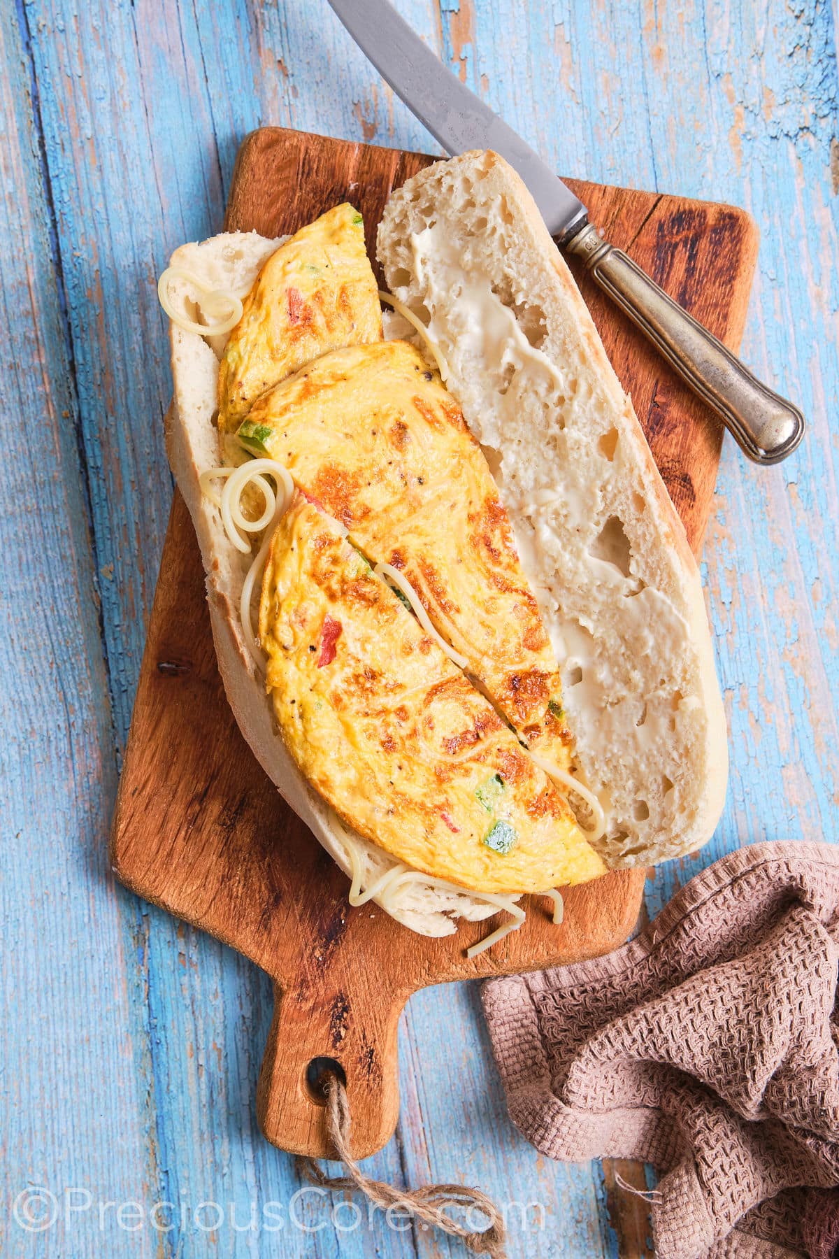 Sliced of spaghetti omelette placed on one side of a baguette.