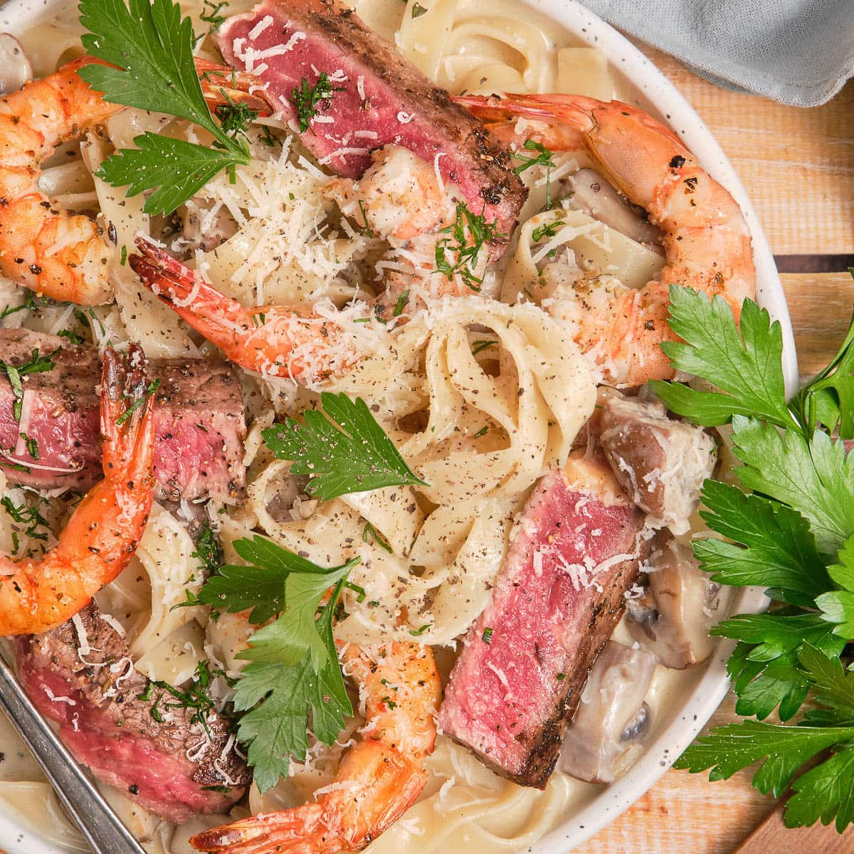 Square image of steak and shrimp pasta.