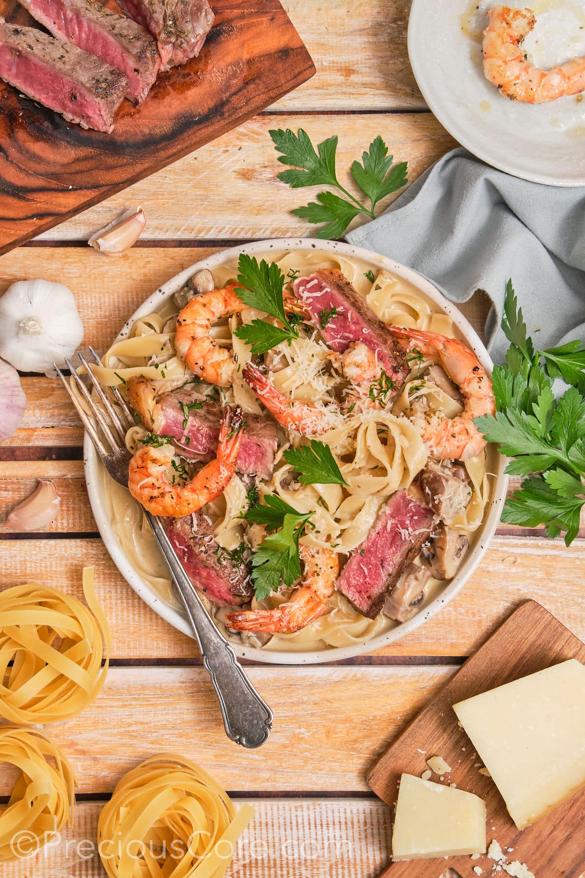 Wide shot of steak and shrimp pasta on a plate.