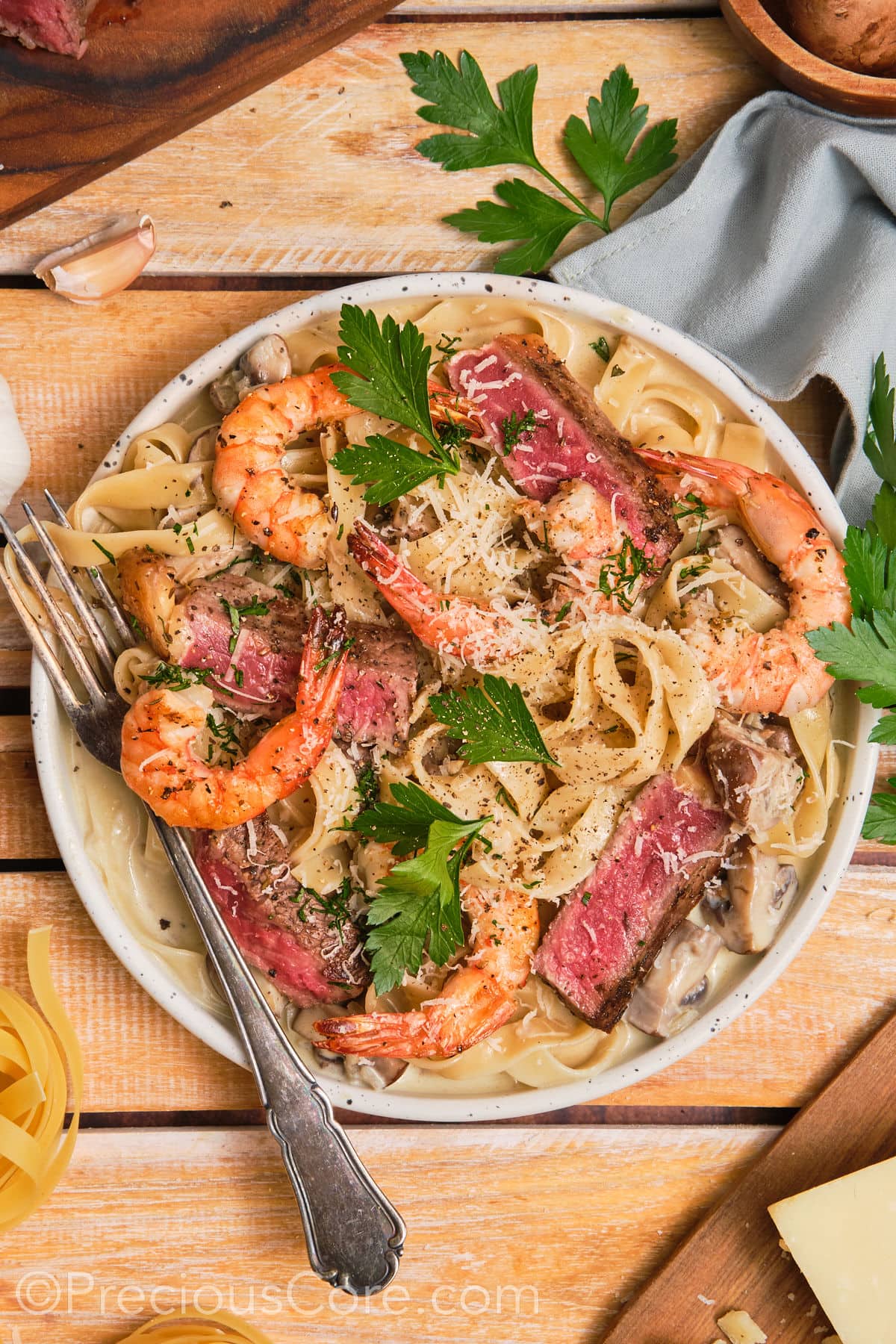 Bowl of steak and shrimp pasta with a fork on the side.