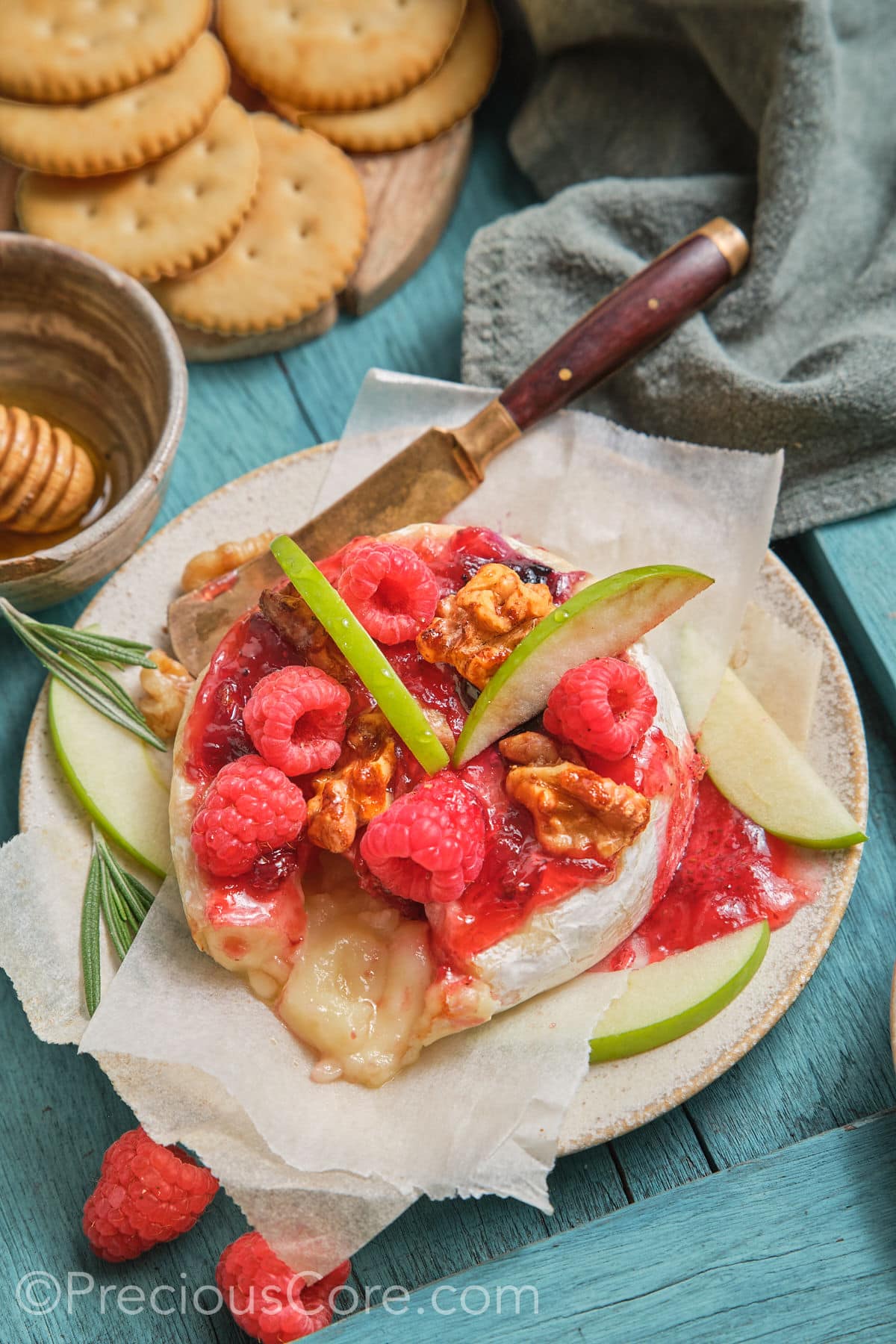 Around baked brie topped with preserves, fresh fruit, and candied walnuts.