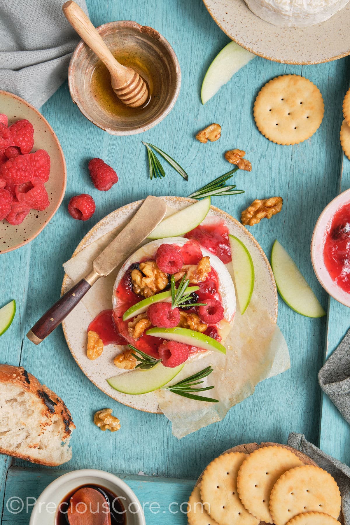 Baked brie and preserves topped with raspberries, fresh raspberries, and apple slices.