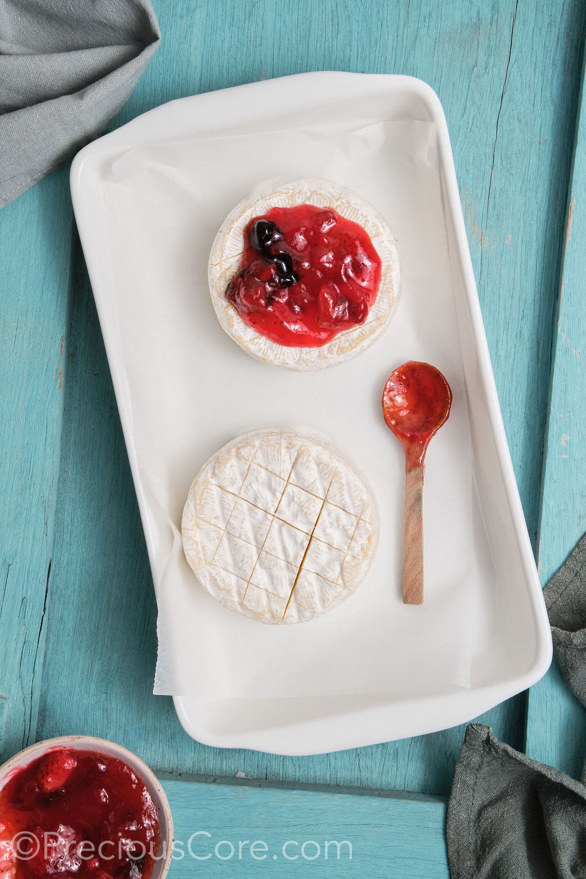 Brie transferred to a baking dish and topped with preserves.,