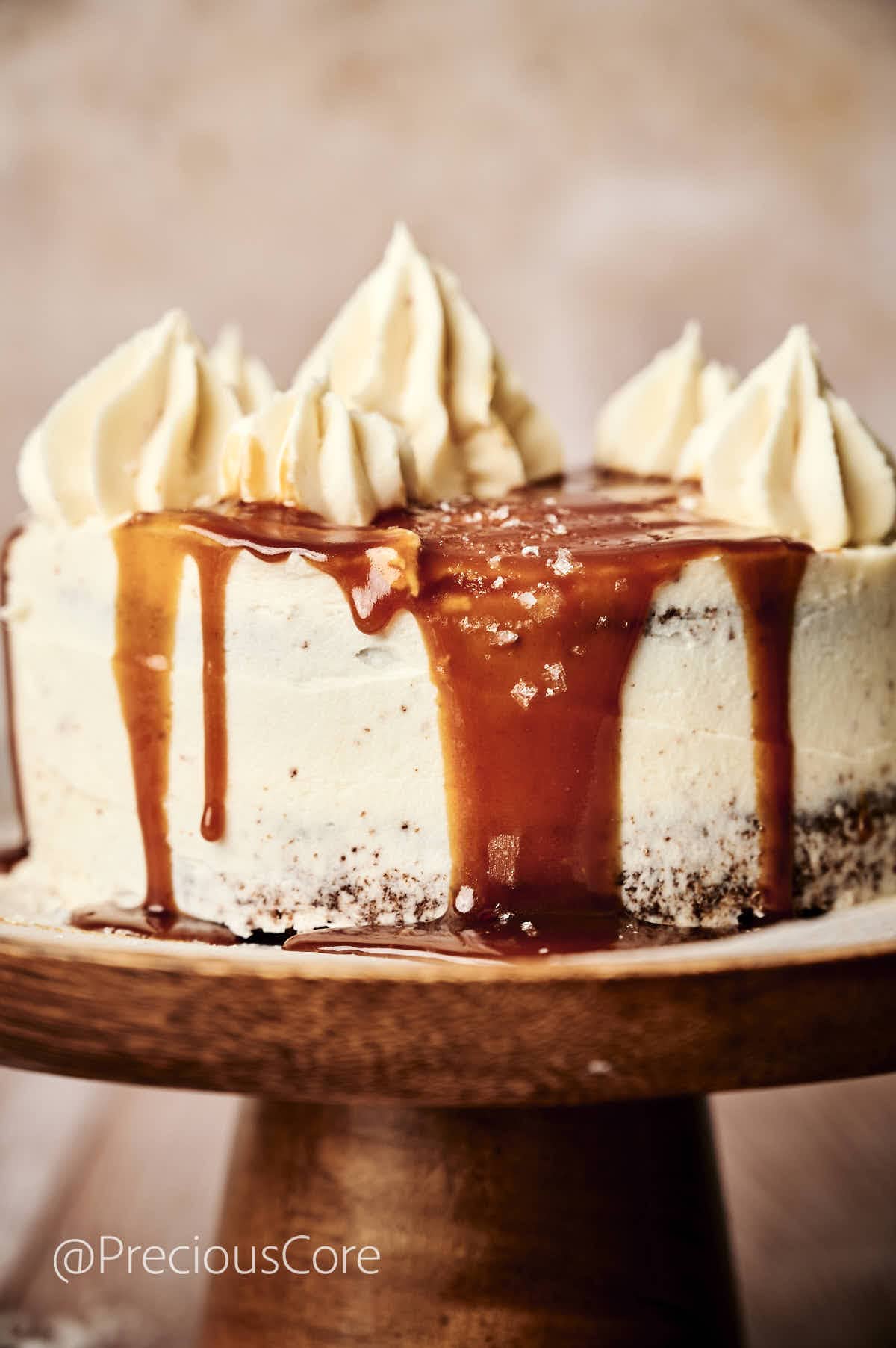 Salted Caramel Cake on a cake stand with caramel dripping down the sides.