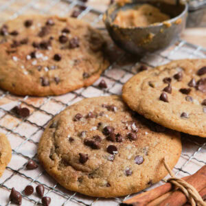 Large cinnamon chocolate chip cookies on oven rack.