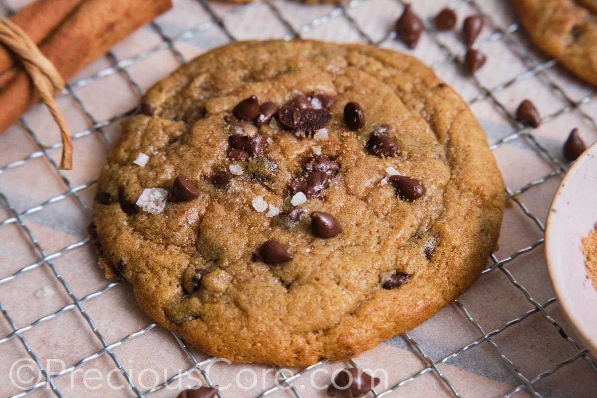 Close up of a large cookie topped with chocolate chips and see salt.