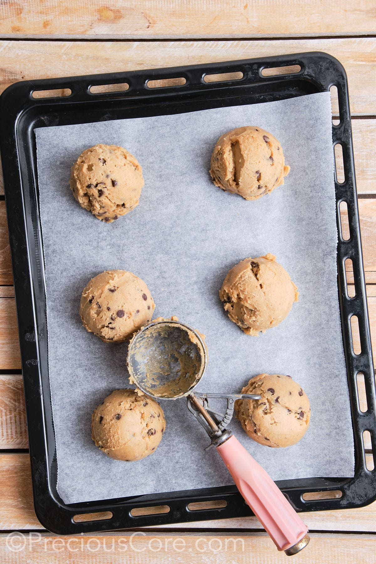 Baking sheet lined with parchment paper with 6 scoops of cookie dough