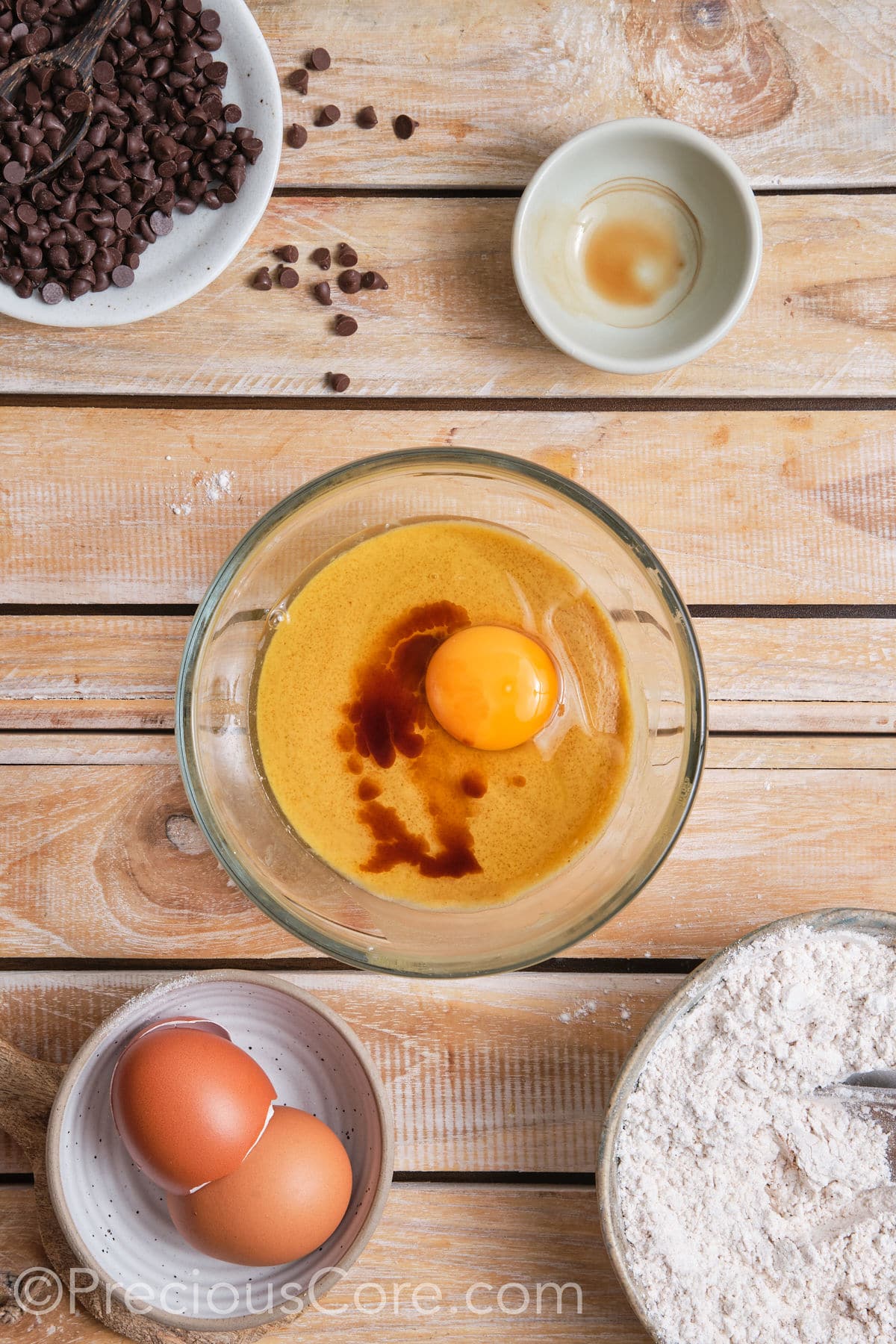 Adding egg and vanilla to the creamed butter and sugar mixture in a bowl. 