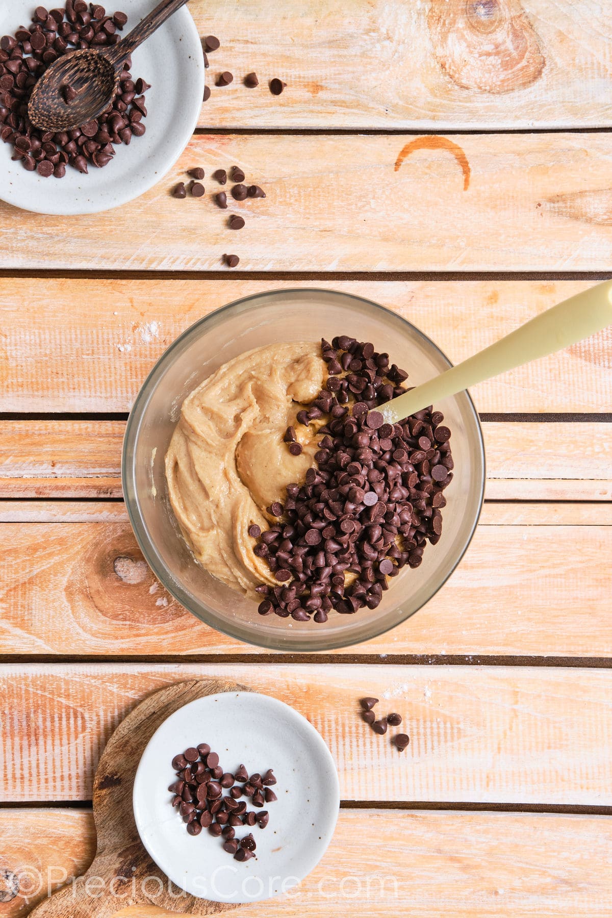 adding chocolate chips to the cookie dough mixture in a bowl. 