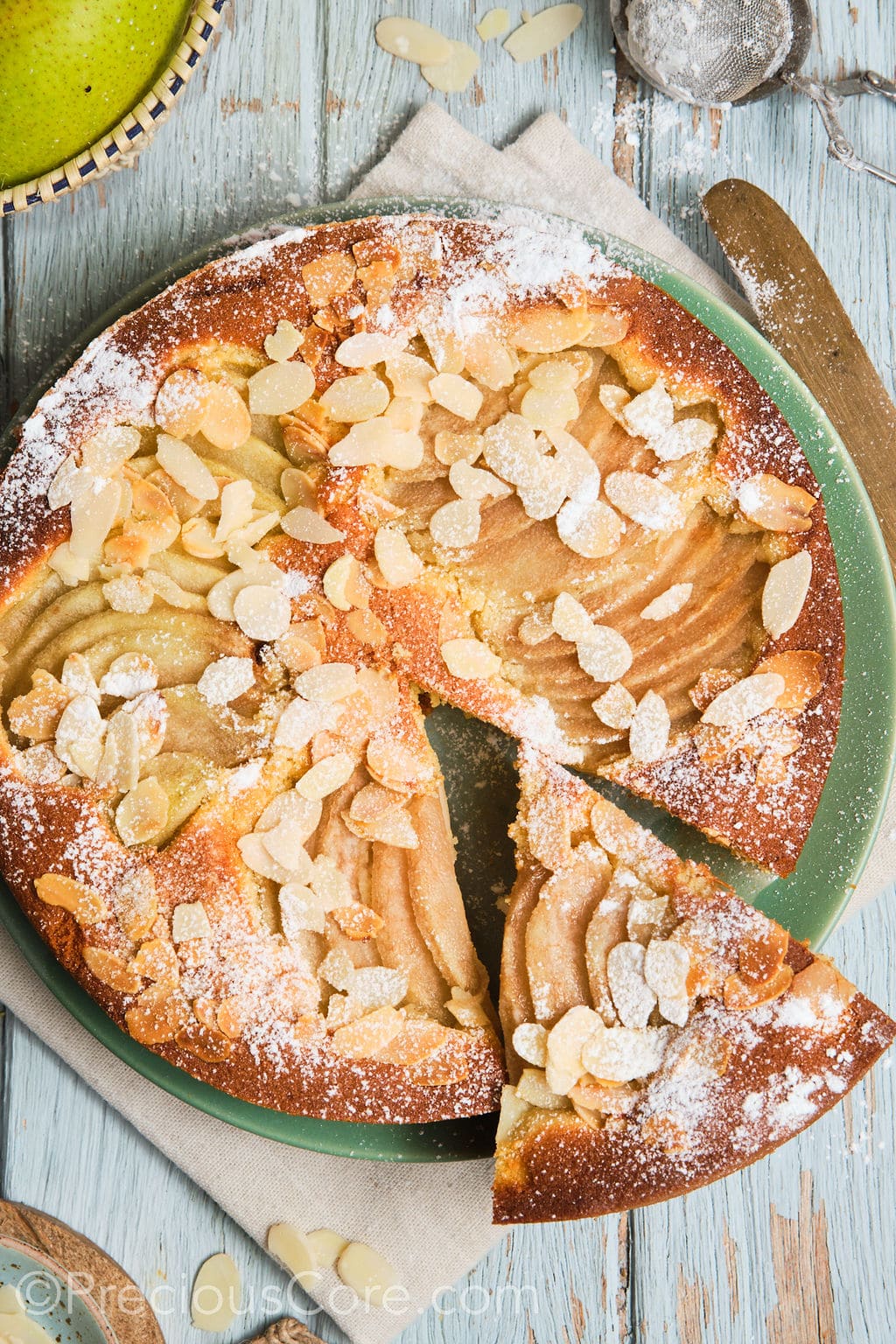 Italian pear almond cake on a plate with a slice cut out.