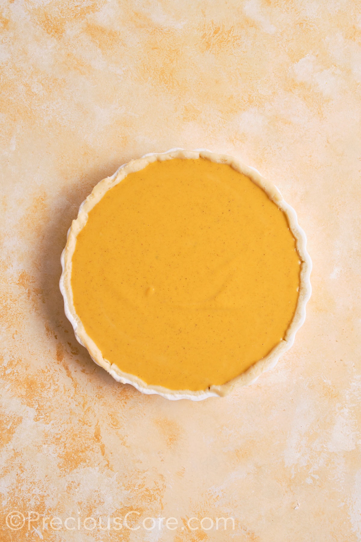 Pumpkin pie filling poured into unbaked pie crust.