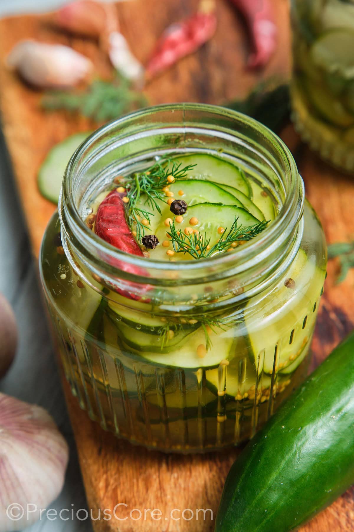 Close-up shot of cucumber in a brine topped with peppercorns and dill.