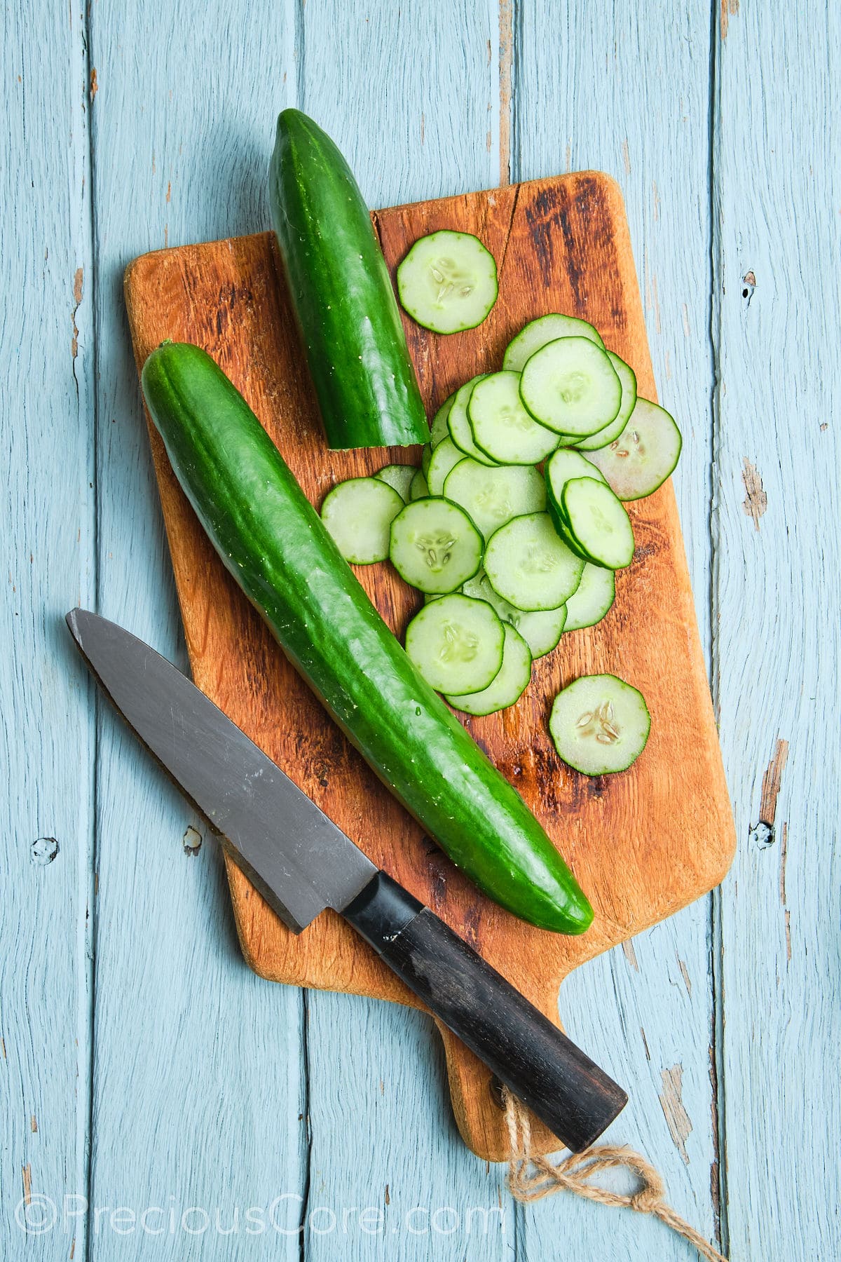 Slicing cucumbers on a cutting board into rounds.