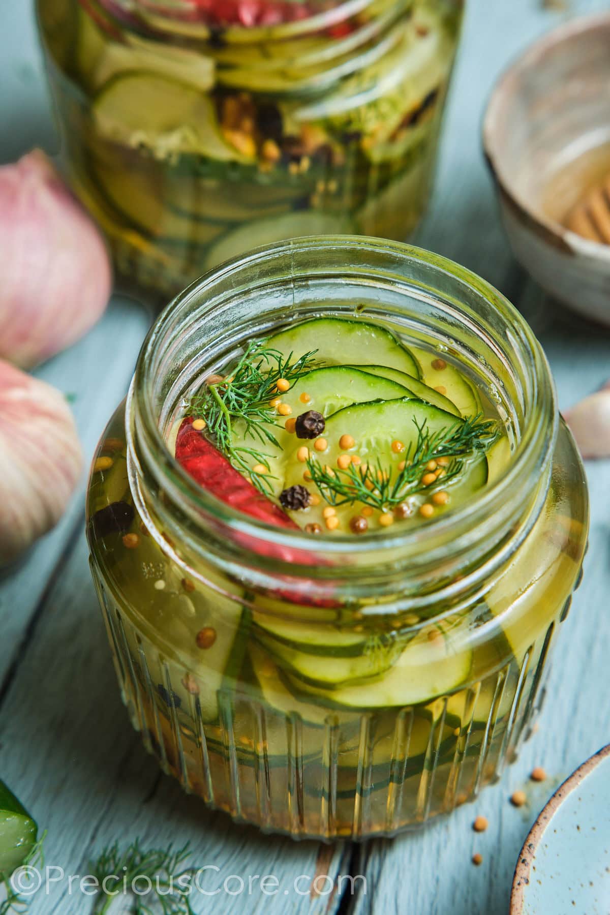 Quick pickled cucumbers in a mason jar with peppercorns on top.