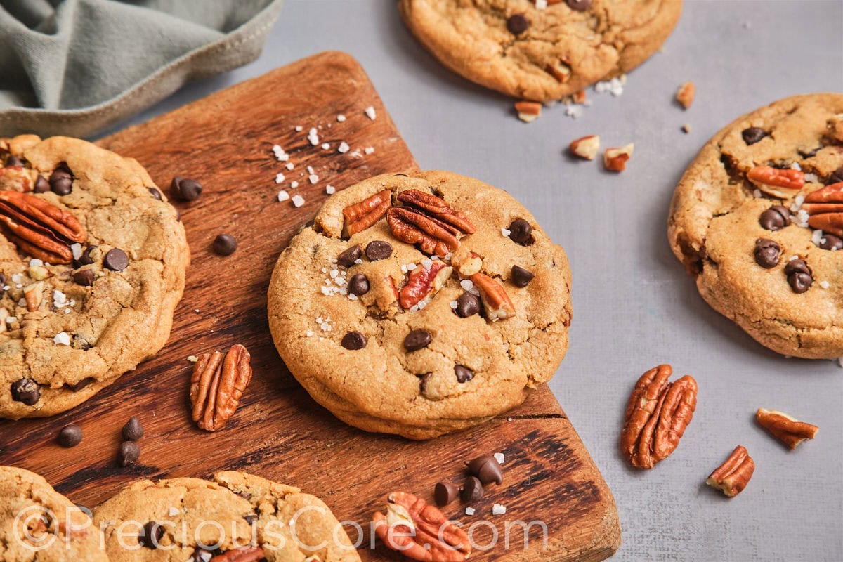 Pecan brown butter cookies topped with chocolate chips on a chopping board. 