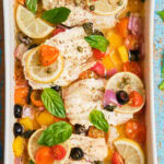 White fish fillets in a casserole dish baked with veggies.