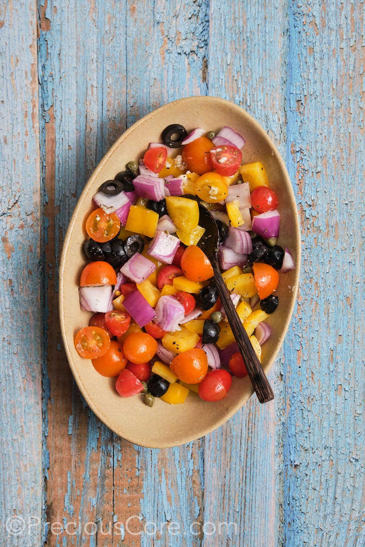 Diced veggies coated in olive oil and seasonings, in a bowl.