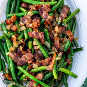 Bacon and green beans on a white tray.