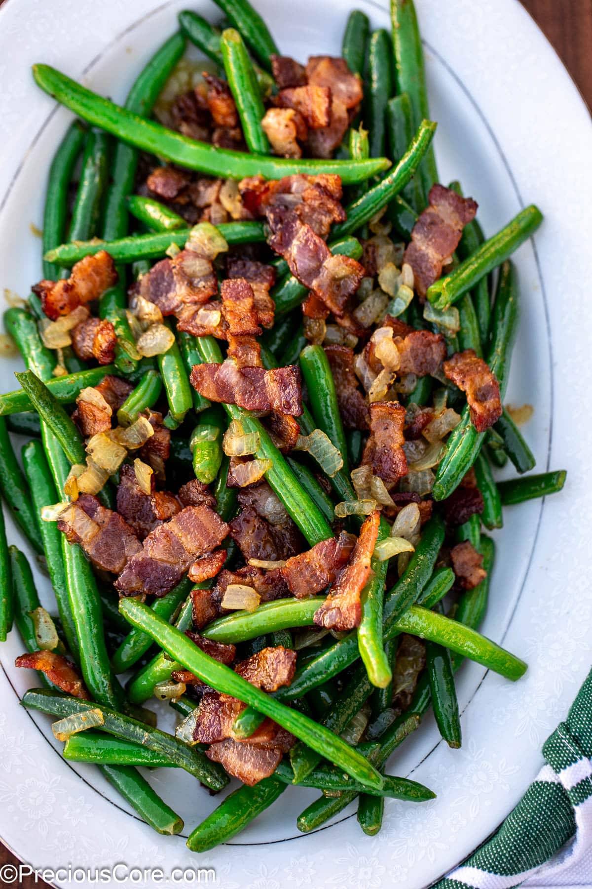 Bacon and green beans on a white tray.