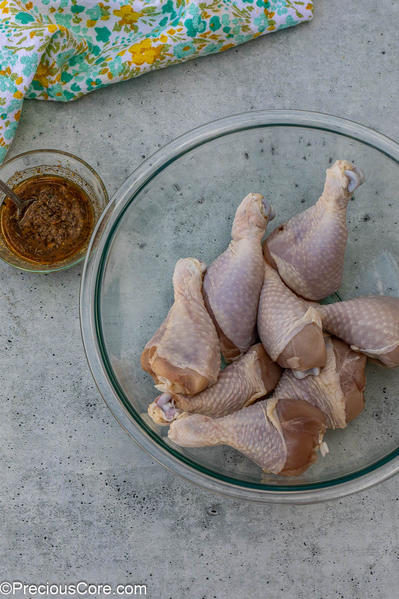 Chicken drumsticks that have been patted dry in a large mixing bowl.