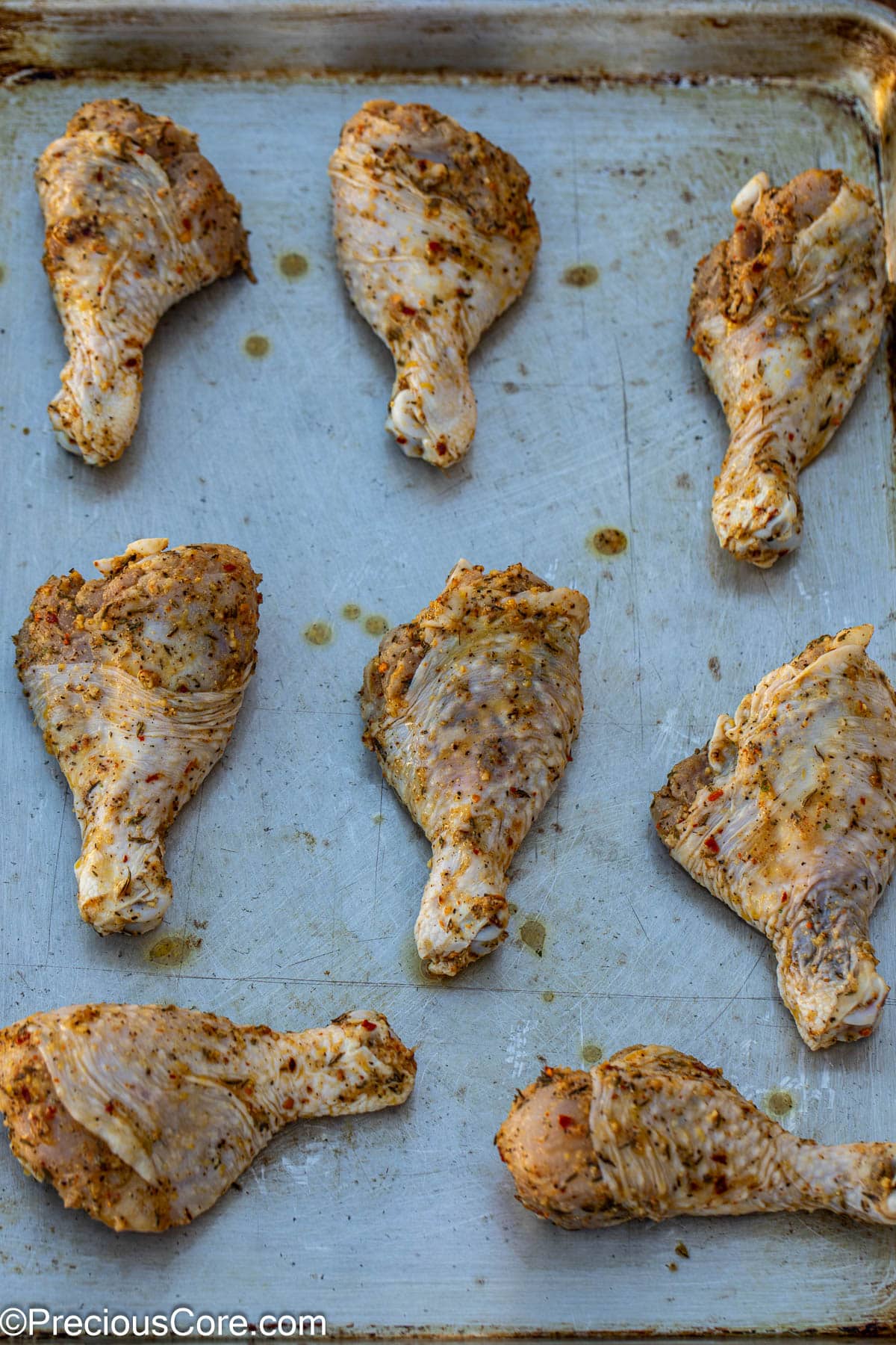 Marinated chicken drumsticks on a baking sheet.