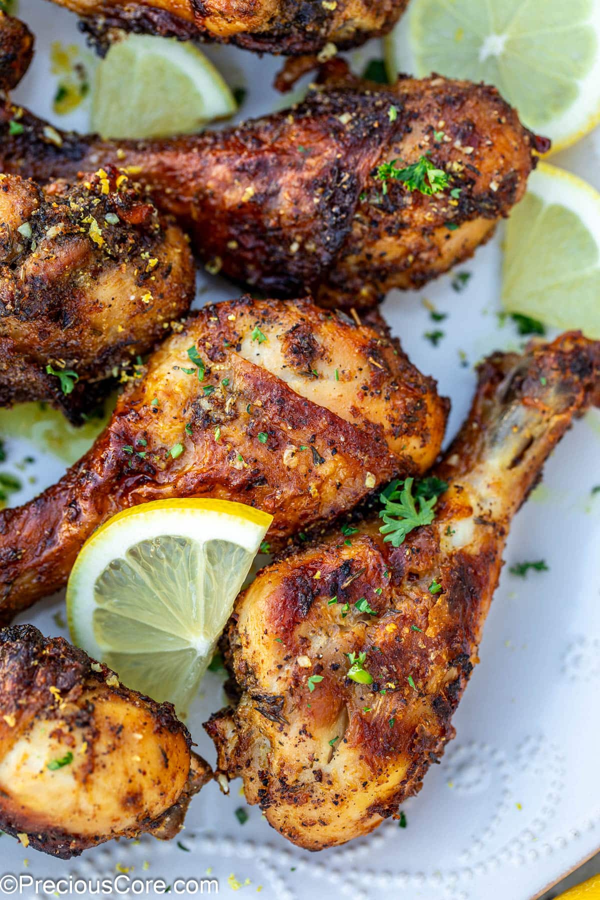 Lemon pepper drumsticks on a plate with lemon slices.