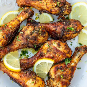 Cooked lemon pepper drumsticks on a white plate.